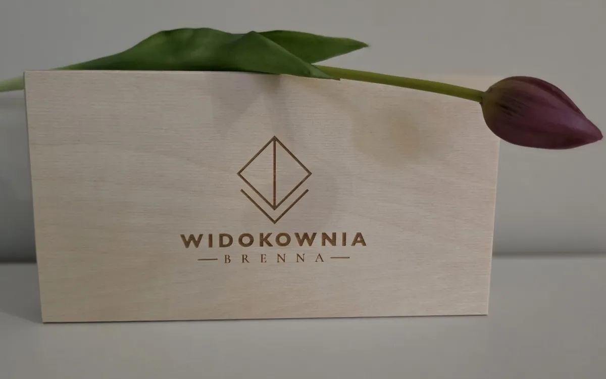 Zamknięte drewniane pudełko z wygrawerowanym logo Widokowni Brenna